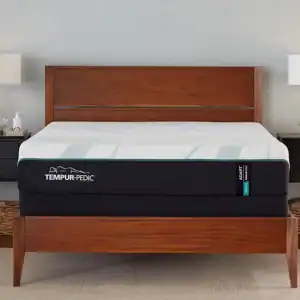 A modern bedroom featuring a king-sized bed with a Tempur-Pedic TEMPUR-Adapt® 11" Medium Mattress, flanked by two black nightstands and matching table lamps, set against a neutral wall.
