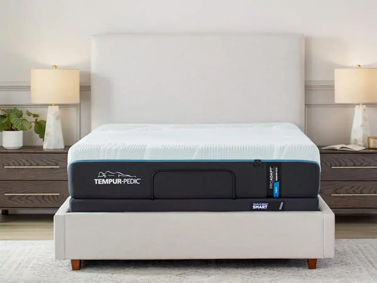 A Tempur-Pedic TEMPUR-ProAdapt® 12" Soft Mattress on a simple white bed frame, set against a light gray wall with two wooden bedside tables on each side, in a neatly arranged bedroom.