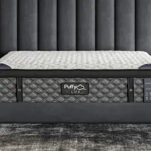 A luxurious Purple Mattress set on a modern gray upholstered platform bed frame, showcased in an elegant bedroom with a dramatic tufted headboard and dark walls, promising a stylish and.