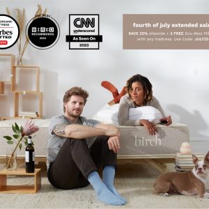 A man and woman relax on a Birch Natural Mattress with a dog in front of them. Text highlights a Fourth of July sale for the Birch Natural Mattress, offering 25% off and two free Eco-Rest Pillows. Three award logos from Forbes, Wired, and CNN are displayed above them.