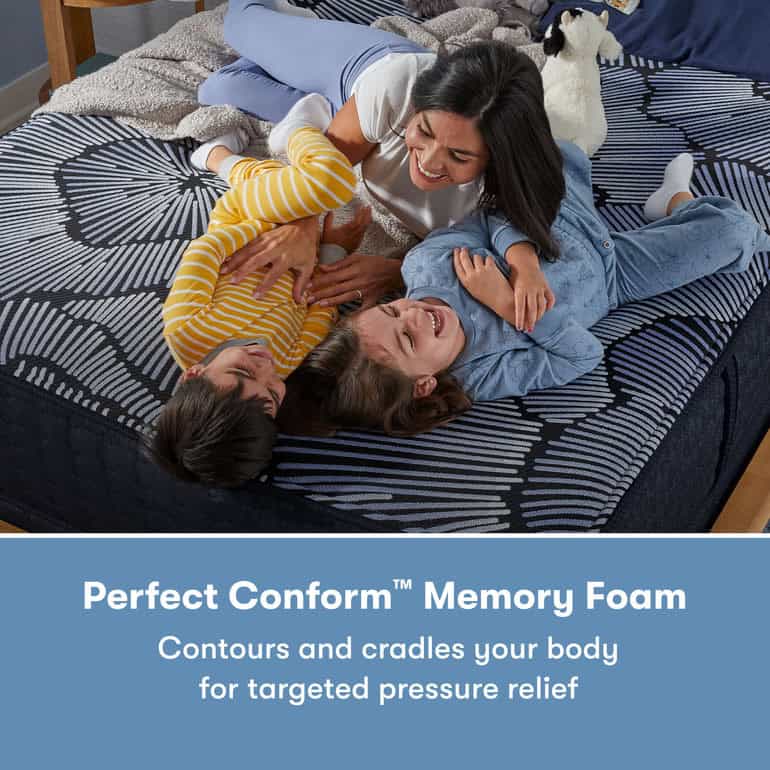 A woman and two children laughing and playing on a bed with a black-and-white patterned mattress. The text reads, "Serta Perfect Sleeper X Hybrid Mattress: Aspen Firm—Contours and cradles your body for targeted pressure relief.
