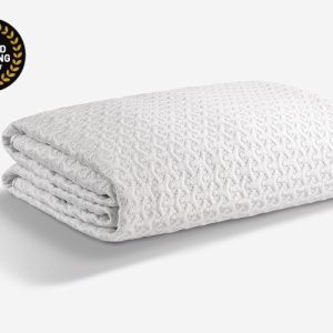 A neatly folded, white, textured Dri-Tec Mattress Protector is displayed against a plain white background. In the top left corner, a black and gold "Award Winning Product" badge is visible, featuring laurel leaves and bold lettering. This could easily serve as an elegant mattress protector.