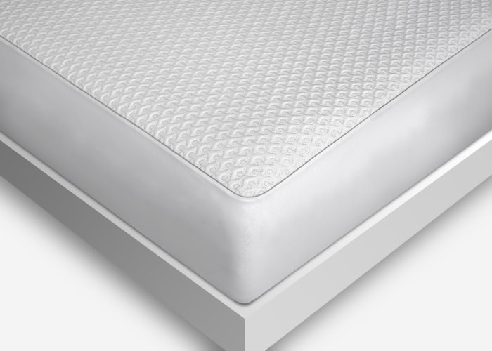 A close-up view of a neatly made bed featuring a mattress with the Dri-Tec Mattress Protector, showcasing its textured white cover. The bed presents a minimalist design with a clean, white frame. The Dri-Tec Mattress Protector includes a subtle pattern that adds an elegant touch to the overall appearance.