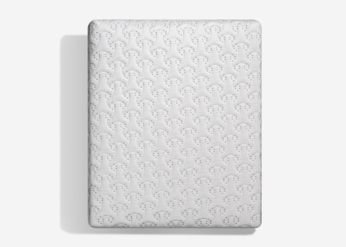 A top-down view showcases a white Dri-Tec Mattress Protector with a textured pattern of interconnected shapes, including small, repeating star-like designs. It casts a slight shadow to the left against a plain background, highlighting its high-quality craftsmanship.