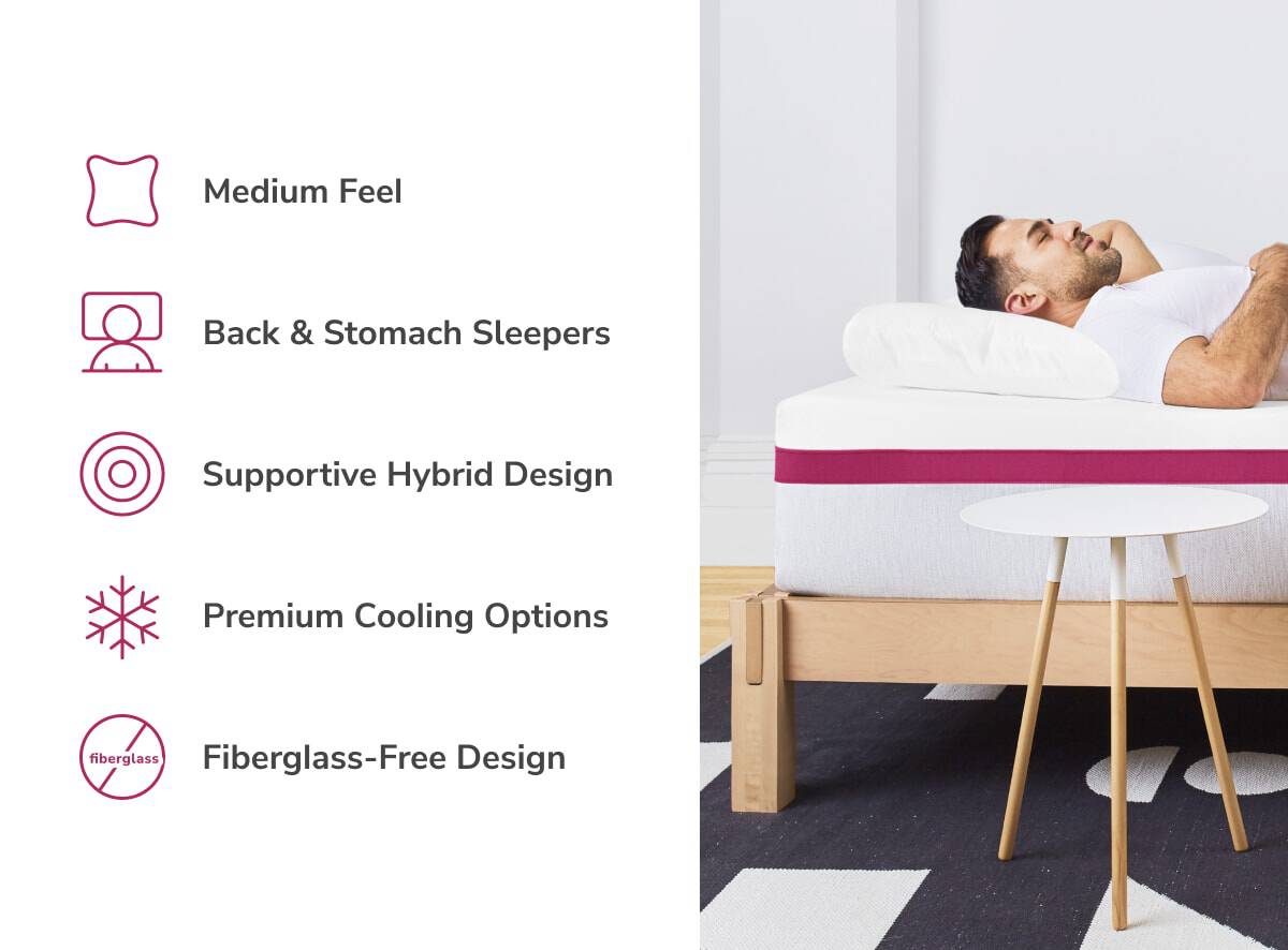 A man relaxes on a Helix Dusk Luxe Mattress, set on a wooden bed frame beside a round white table. It features a medium feel, ideal for back and stomach sleepers, with supportive hybrid design, premium cooling, and fiberglass-free construction.