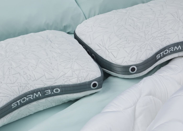 Two TEMPUR-Breeze® ProHi Pillows with geometric patterns rest side by side on a bed with light blue sheets and a white comforter, providing luxurious comfort.
