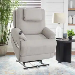 A light gray Zecliner Model 2 Petite — Power Sleep Chair (Copy), partially elevated with a remote, sits on a patterned rug beside a round black side table with a lamp and plants in a bright, modern living room.