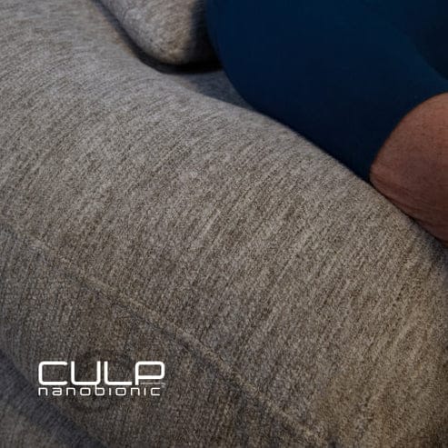 A close-up of a gray fabric sofa, Model 2 Plus Shell Exclusive, with a person’s arm in a dark blue sleeve resting on it. The "Culp nanobionic" logo appears in the lower left corner.