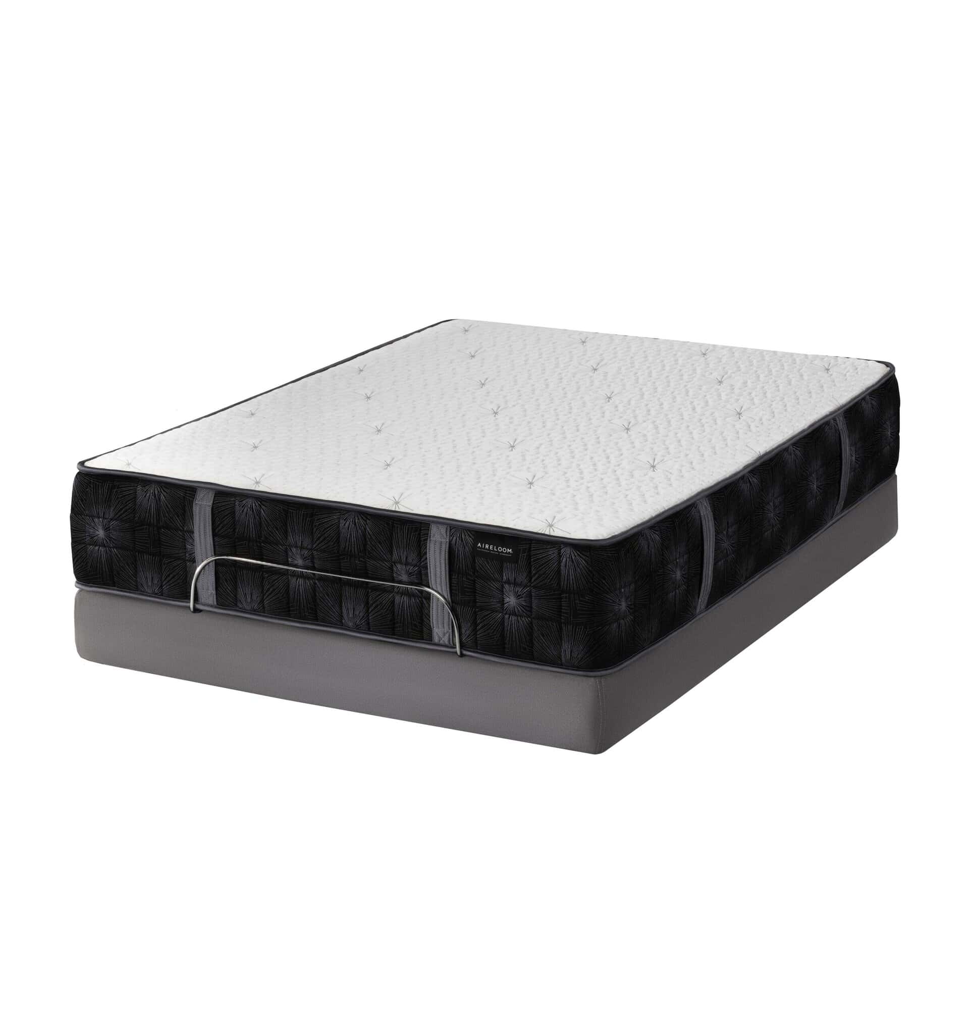 The Summit Luxury Firm mattress features a thick, white quilted top and black patterned sides on a gray box spring, offering firm support and luxury comfort—shown isolated on a white background.