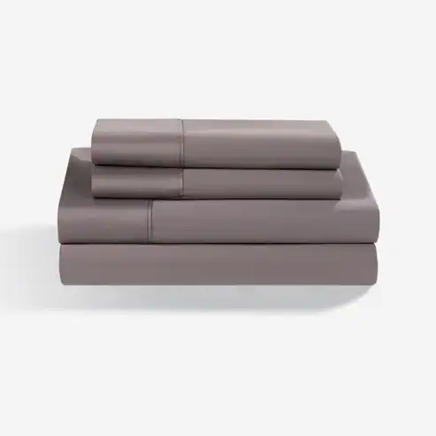 A neatly folded set of Hyper - Cotton Performance Sheets in grey, including two pillowcases, a flat sheet, and a fitted sheet, stacked on a white surface against a plain white background.