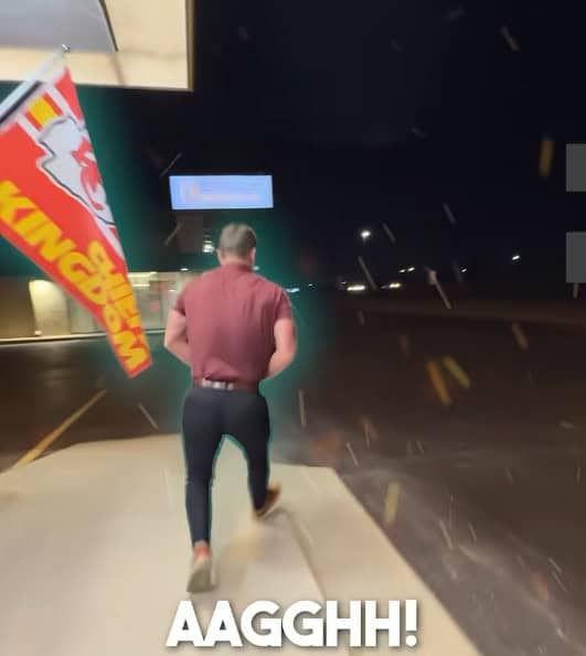 A person in a red shirt and dark pants runs outside at night near a Burger King sign, with a Kansas City Chiefs flag and "AAGGHH!" at the bottom—maybe they just heard about the Fall Savings Event for better sleep!.