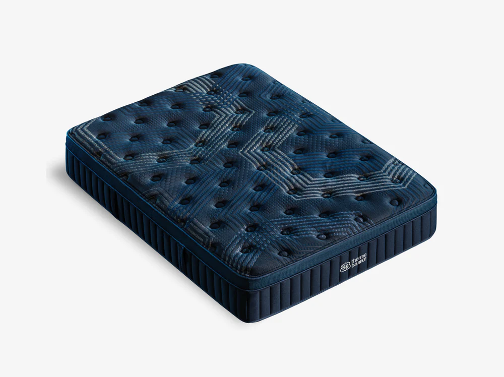 The ThermoBalance Soft mattress, in dark blue with a geometric tufted surface, features vertical side stitching, a small brand label, and ThermoBalance technology for enhanced comfort; shown against a plain white background.