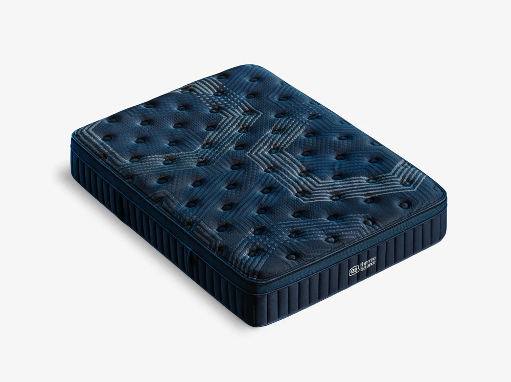 The ThermoBalance Elite mattress appears in dark blue with a quilted geometric pattern, circular tufting, and a side panel featuring vertical stitching and a small white logo, set against a plain white background.